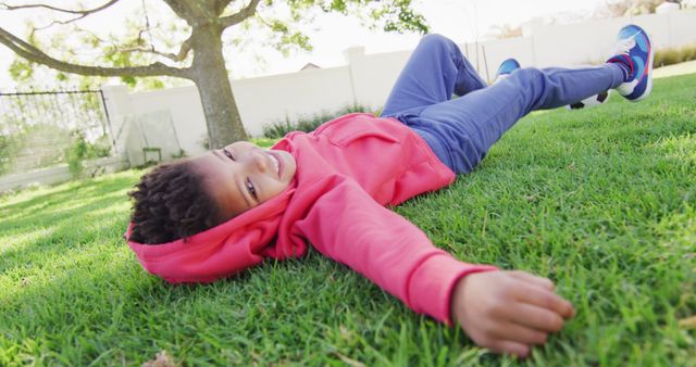 Portrait of happy african american boy laying on grass in garden. Spending quality time at home.