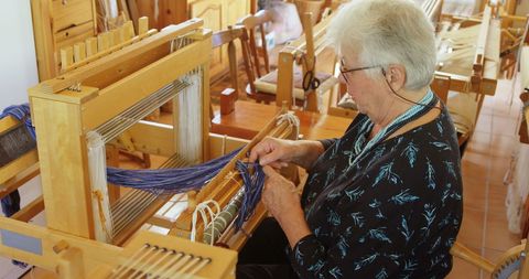 Elderly Woman Working at Hand Loom in Cozy Workshop