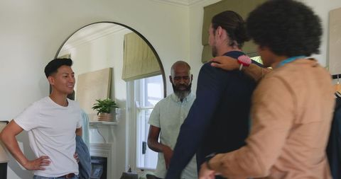 Friends helping groom prepare in home setting