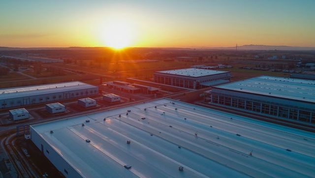 Aerial warehouse complex glowing at sunrise with rooftop hvac units and service roads