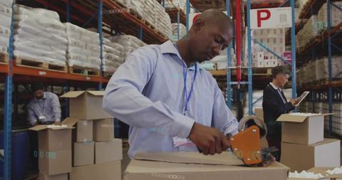 Warehouse worker sealing cardboard box with tape dispenser in logistics hub