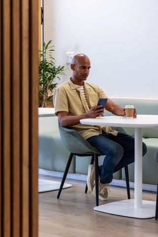 Modern coworking lounge professional enjoying takeaway coffee while checking smartphone