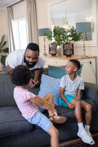 Father playing with children on sofa in cozy living room