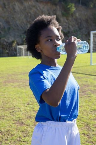 Young athlete boosting energy during soccer practice with water bottle