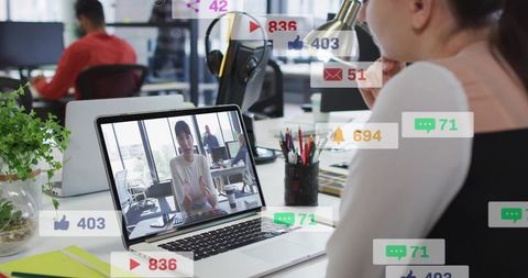 Coworkers joining virtual meeting in open-plan office with social media notifications