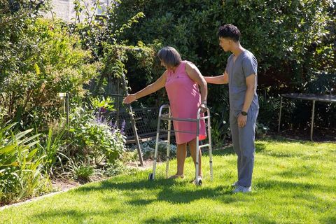 Senior Woman with Caregiver Enjoying Garden Using Walker