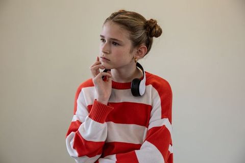 Thoughtful preteen wearing striped sweater and headphones