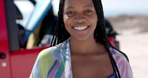 Joyful Woman on Sunny Road Trip to Beach with Red Car Background