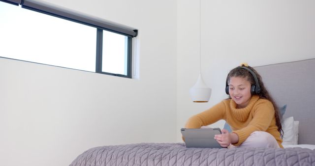 Happy Biracial Girl Using Tablet and Headphones on Bed - Download Free Stock Images Pikwizard.com