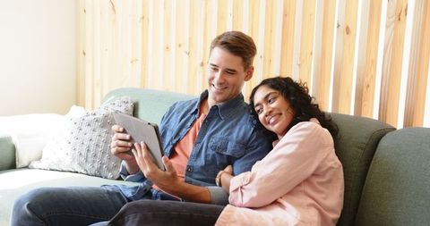 Happy Couple Relaxing on Sofa Sharing Tablet