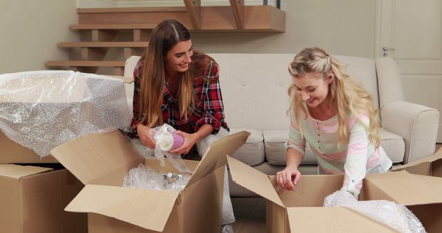 Smiling women opening boxes in new house