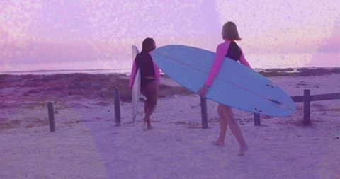 Friends Surfing at Dusk with Surfboards Walking along Shore