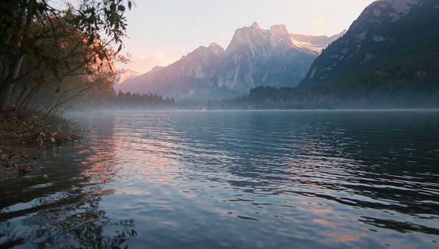 Tranquil Sunrise Over Misty Lake with Mountains in Background