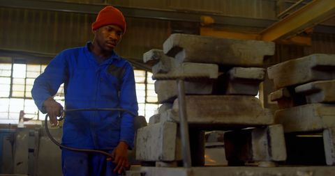 Worker using blow torch to heat metal mold in foundry workshop