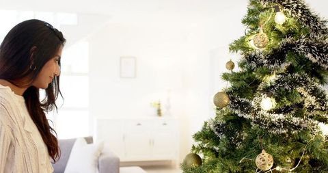 Woman Enjoying Christmas Tree Decorations in Cozy Living Room