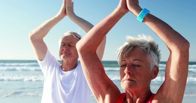 Senior couple practicing yoga on sunny beach demonstrates calming and wellness activities ideal for fitness, health, lifestyle, and travel-related projects. Useful for promoting senior health, mental well-being, and active lifestyles.