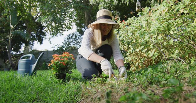 Caucasian woman wearing a hat and gardening gloves gardening in the garden. lgbt relationship and lifestyle concept