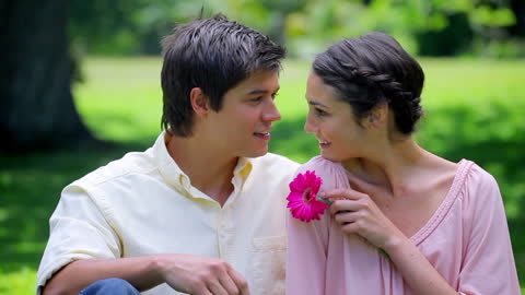 Happy Couple Relaxing in Nature Holding Flower