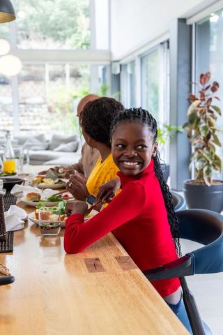 Sunlit modern kitchen family breakfast at wooden bar happy teen girl smiling over shoulder