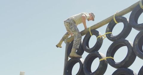 Determined Soldier Climbing Army Obstacle Course Tyre Wall