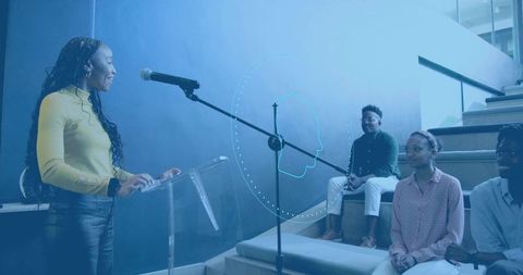 Young Woman Presenting at Campus Stairs with Microphone and Engaged Student Audience