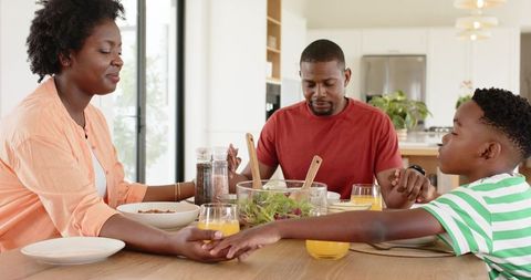 African american family holding hands at breakfast table showing unity and gratitude