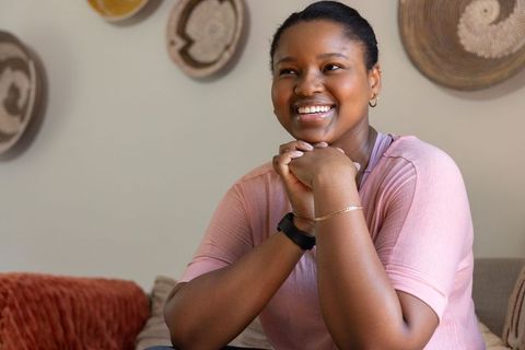 African american woman smiling on sofa in cozy neutral living room with woven decor