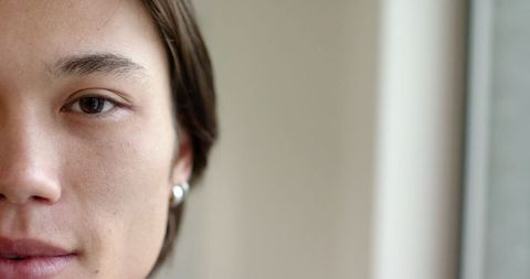 Half face portrait of man with silver hoop earring by window