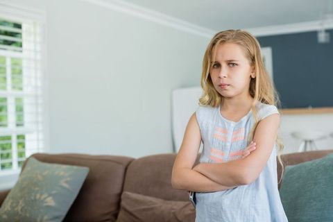 Serious Young Girl with Crossed Arms in Modern Living Room