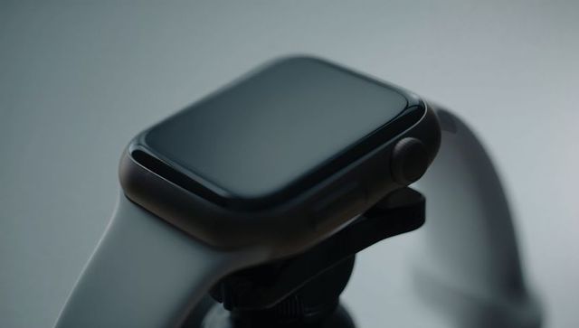 Displaying dark gray smartwatch on stand showing crown and silicone band