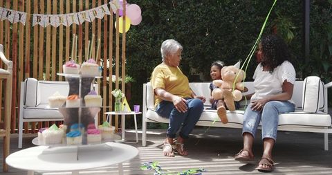 Multigenerational family celebrating birthday on patio with cupcakes and teddy bear