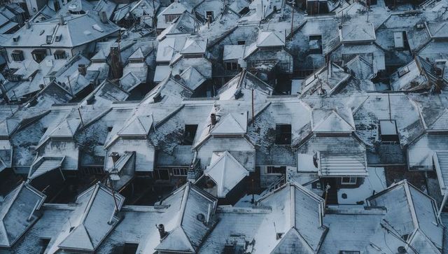 Snow-dusted rooftop grid forming geometric winter pattern over dense urban neighborhood