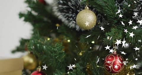 Christmas tree closeup sparkling with warm lights hanging gold glitter and red swirl baubles