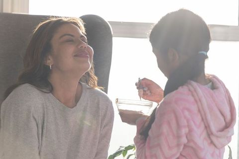 Backlit mother and daughter sharing warm morning bond over bowl and spoon in cozy home