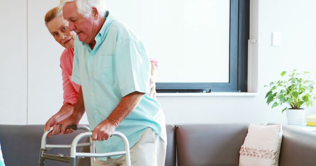 Senior man using walker assisted by female caretaker in living room - Download Free Stock Images Pikwizard.com