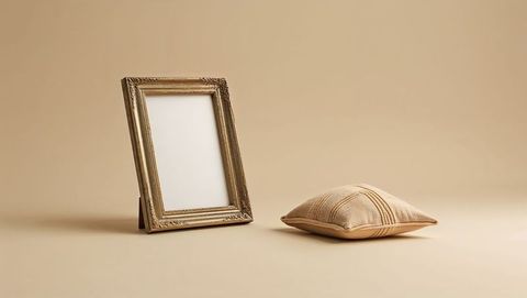 Elegant gold frame and cushion on soft beige background