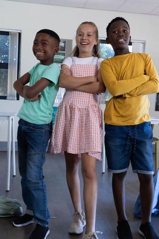 Preteen classmates standing confident with arms crossed showing teamwork and diversity