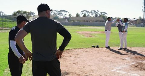 Coaches coaching baseball team on neighborhood diamond during sunny practice session