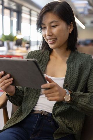 Asian Woman Using Tablet in Modern Office Lounge