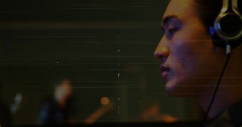 Musician wearing headphones in recording studio with blurred background