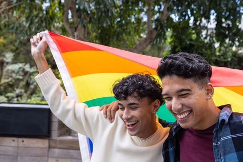 Friends Celebrating Holding Rainbow Pride Flag in Outdoor Setting