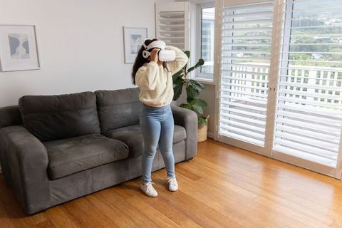 Young girl wearing vr headset exploring virtual world in bright modern living room