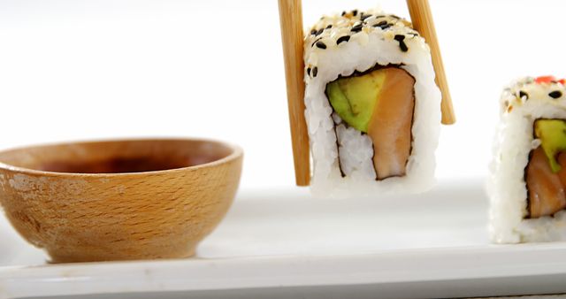 Chopsticks Lifting Sushi Roll with Avocado and Salmon - Download Free Stock Images Pikwizard.com