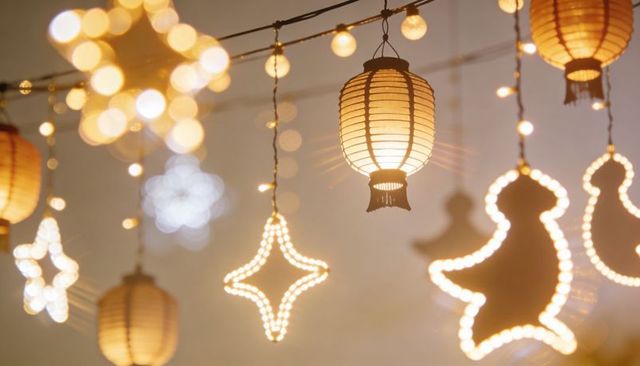 Warm hanging paper lanterns and led star lights creating soft bokeh festive ambience