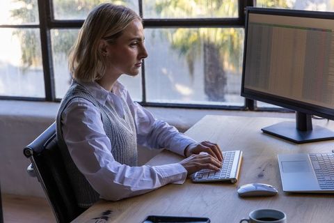 Woman Typing on Keyboard in Bright Office by Window