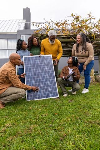 African american family examining solar panel in front yard discussing home energy upgrade