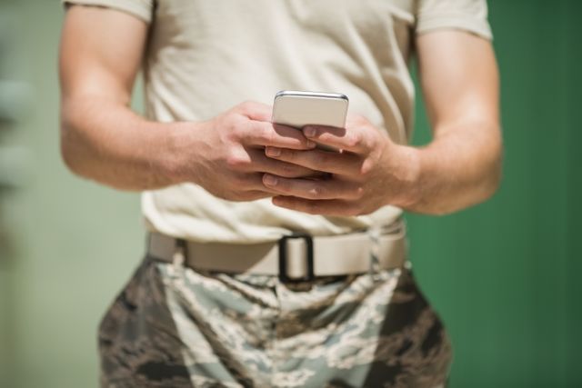 Mid section of military soldier using mobile phone in boot camp