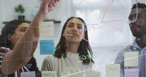Diverse Team Collaborating on Glass Board Strategy in Modern Office