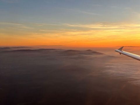 Golden sunrise over mountain range and beach from airplane