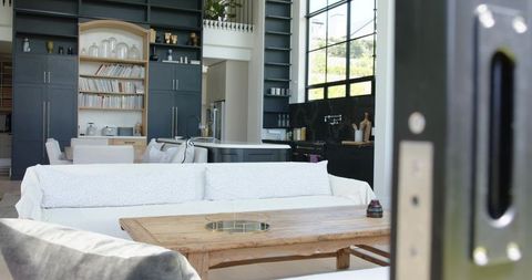 Showcasing bright open-plan living with white slipcover sofa and dark kitchen cabinetry